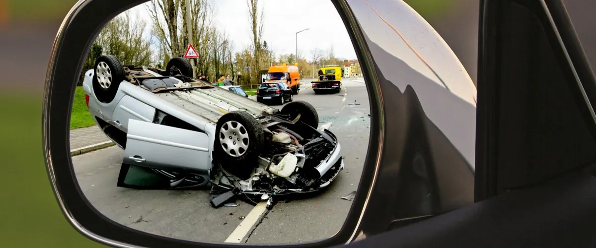 Voiture accidentée retournée sur la chaussée, vue dans un rétroviseur