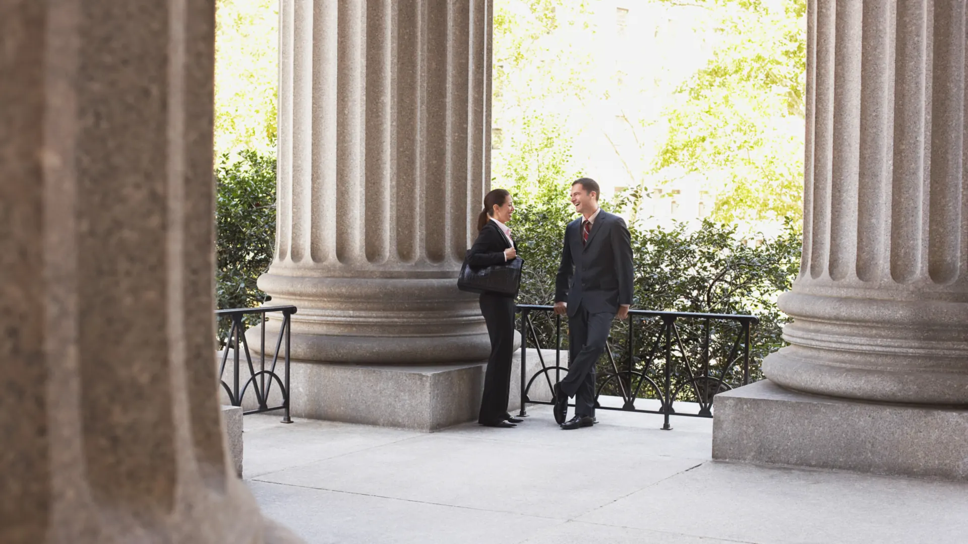 Deux avocats échangent entre les colonnes d'un palais de justice