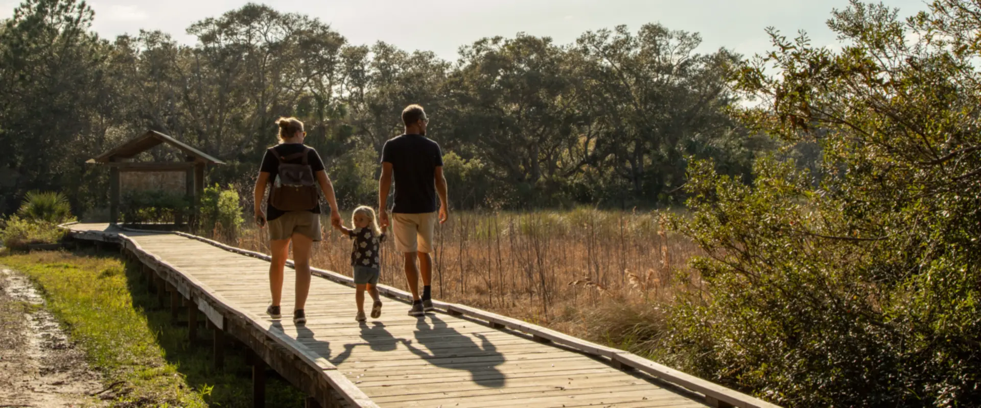 Parents et enfant marchant main dans la main sur un ponton en bois
