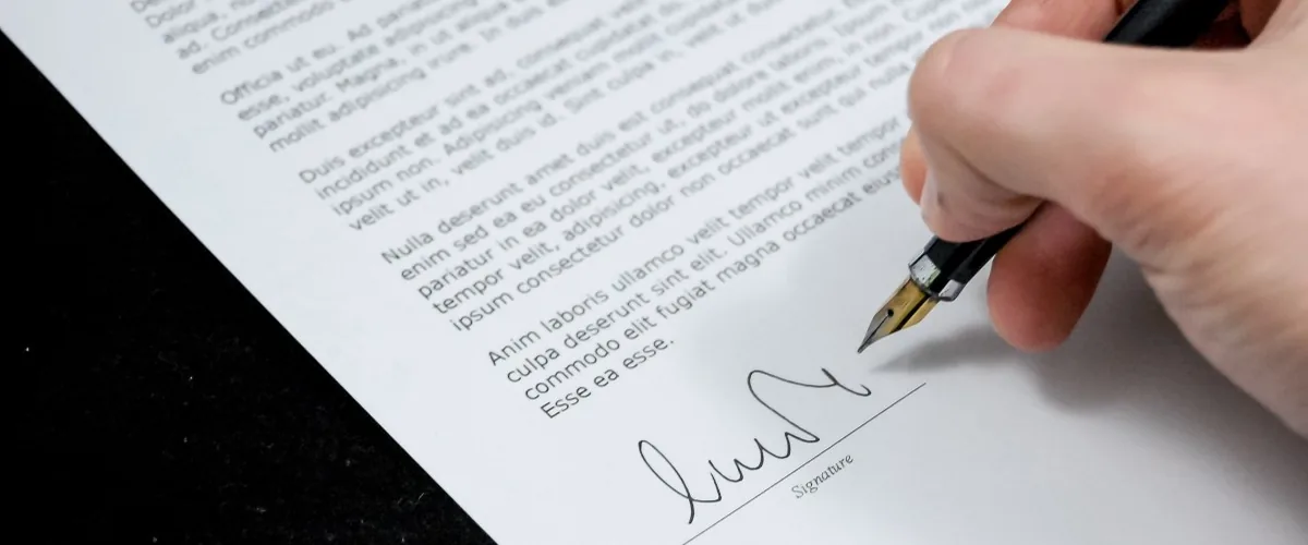 Main signant un acte au stylo plume